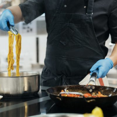 front-view-chef-with-gloves-cooking-pasta-kitchen